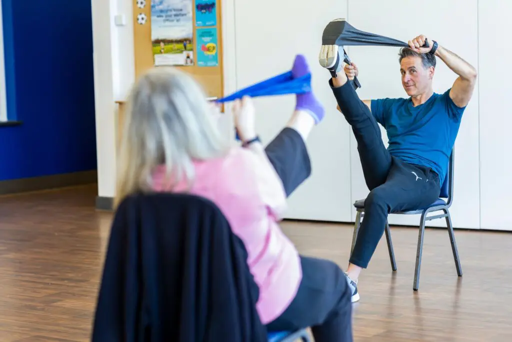A fitness trainer and Lifestyle Coordinator conducting an exercise class for elderly people as part of the care home activities